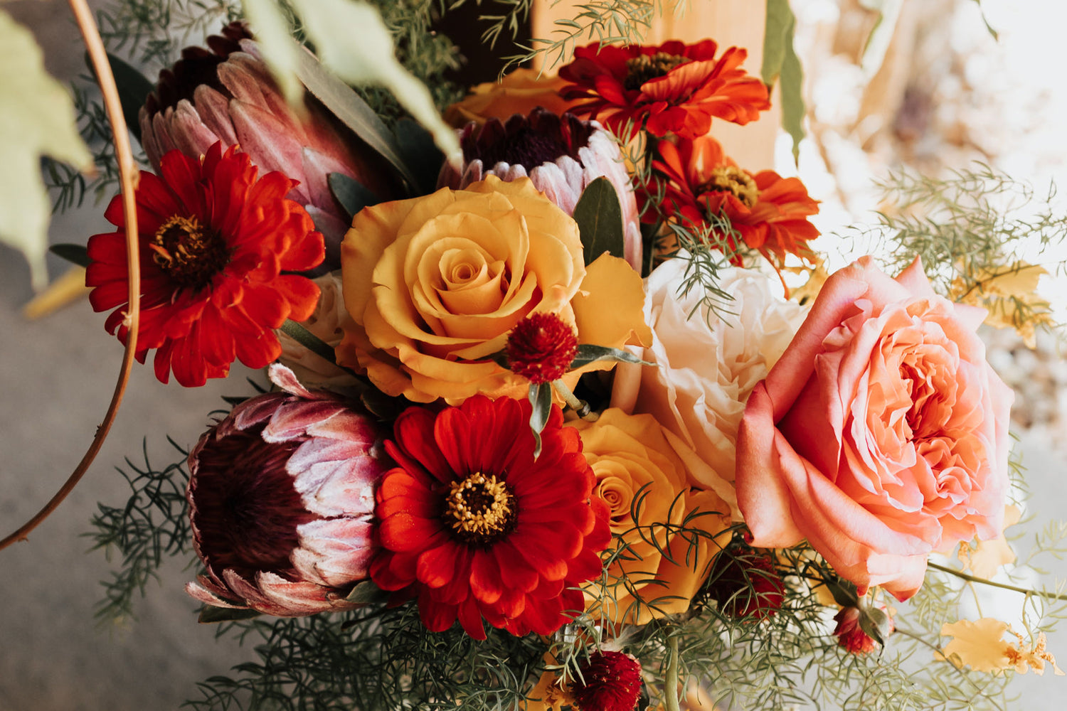 Artichokes & Pomegranates flower arrangement with pink ice protea, dahlias, roses and oncidium orchids.