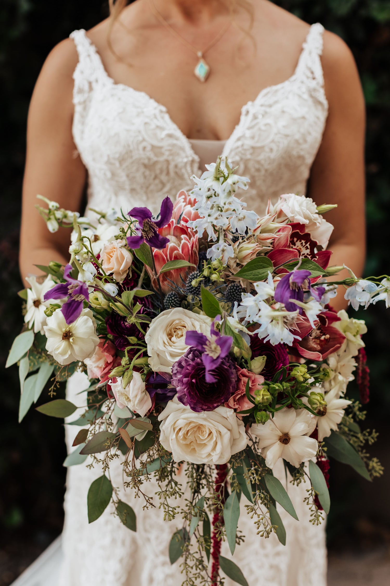 Artichokes & Pomegranates designed bridal bouquet with pink ice protea, butterfly ranunculus, delphinium, roses, cymbidium orchid, blushing bride protea, clematis and lisianthus.